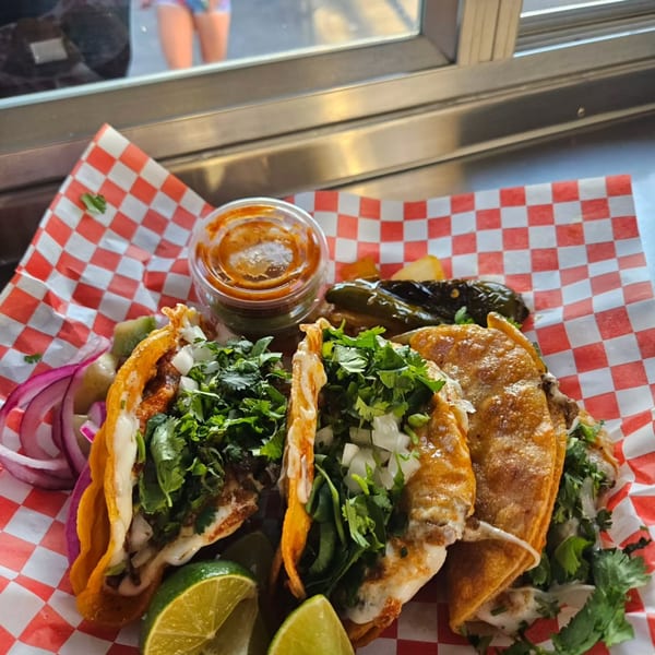 Garrafa's birria tacos with cilantro, onions, lime, pickled jalapeños, and a side of consommé.